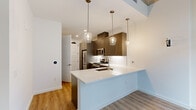 This well-appointed two-story residence offers a thoughtfully designed layout across two floors, combining contemporary aesthetics with functional living. The kitchen is a standout feature, showcasing grey shaker-style cabinetry, white quartz countertops, a classic subway tile backsplash, and a full suite of stainless steel appliances including a gas range, built-in microwave, refrigerator, and dishwasher. Elegant pendant lighting and a peninsula with a sink add both style and practicality to the space. Light wood-tone flooring flows consistently throughout, complementing the clean, modern palette of white walls and grey accents. The living areas are distinguished by exposed concrete ceilings and expansive floor-to-ceiling windows and glass doors that invite abundant natural light and provide views of the surrounding urban streetscape. The primary bedroom is generously sized and benefits from the same bright, open character. Each of the four bathrooms is finished with grey vanity cabinetry, white quartz countertops, framed mirrors, and wood-look flooring. Walk-in closets with built-in shelving and hanging rods provide ample storage. The multi-level floor plan is connected by two staircases, offering a spacious and versatile living environment throughout.