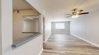 This 2-bedroom, 1-bathroom single-floor unit offers a clean, modern aesthetic with wood-look vinyl plank flooring that runs consistently throughout all rooms, complemented by neutral gray and beige wall tones and crisp white baseboards. The open layout connects two hallways that guide residents through the space efficiently.

The kitchen is well-appointed with white shaker-style cabinetry, granite-look countertops, a double stainless steel sink, and matching upper and lower cabinet storage — providing ample workspace and organization. A full-size refrigerator is included.

The living room is a generously sized open area that receives natural light through a window with outdoor views of surrounding greenery. Both bedrooms feature the same wood-look flooring and neutral tones, with windows that allow natural light to filter in. The primary bedroom offers a comfortable footprint, while the second bedroom includes closet access and additional window views.

The bathroom is neatly finished with a white shaker-style vanity, a framed mirror, a soaker tub-shower combination, and wood-look flooring that ties the space together. Throughout the unit, the consistent use of modern finishes and a neutral color palette creates a cohesive, move-in-ready living environment.