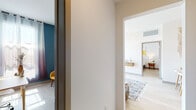 Located in the heart of Los Angeles, this single-floor residence at 1265 Stearns Dr offers a thoughtfully designed living space with modern finishes throughout. The open-concept kitchen is a standout feature, equipped with stainless steel appliances including a gas range, over-the-range microwave, side-by-side refrigerator, and dishwasher. Two-toned cabinetry — white uppers paired with rich wood-grain lowers — frames crisp white countertops and a classic subway tile backsplash, creating a clean, contemporary aesthetic. Light hardwood-style flooring flows throughout the unit, enhancing the bright and airy atmosphere. The living area is generously proportioned with elevated ceilings, recessed lighting, and expansive floor-to-ceiling sliding glass doors that open to a balcony with sweeping Los Angeles skyline views. A secondary room features a bold teal accent wall and ample natural light, ideal for use as a bedroom or home office. The primary bedroom is calm and well-appointed, with access to adjacent living areas. Two bathrooms serve the space — one full bath with a tub-shower combo and backlit vanity mirror, and a second bath with a walk-in shower and matching vanity — both finished in warm wood cabinetry and neutral tile. A central hallway connects all rooms with ease, completing this well-organized and stylish Los Angeles residence.