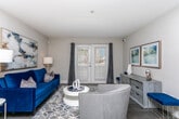 Located on Pelot Drive in East Point, Georgia, this single-floor unit offers a thoughtfully designed layout with a cohesive navy blue and gray color palette carried throughout every room. The open-concept living and dining area is anchored by dark hardwood-style flooring, a bold blue velvet sofa, abstract wall art, and a round marble-top dining table, creating an inviting and modern atmosphere. The space flows naturally into a galley-style kitchen outfitted with white cabinetry, stone-look countertops, a subway tile backsplash, and black appliances including an electric range and full-size refrigerator.

The primary bedroom features plush carpet, a tufted upholstered headboard, navy bedding, and a window allowing natural light to filter in. A second bedroom mirrors this refined aesthetic with similar furnishings and a window overlooking greenery. A third bedroom is configured with a white bunk bed and carpeted floors, making it well-suited for additional guests. The bathroom offers a wide granite-topped vanity with a large mirror and white cabinetry, complemented by dark hardwood-style flooring. Throughout, the unit maintains a clean, well-appointed character.