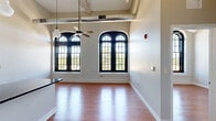 This one-bedroom, one-bathroom residence at 815 Court St in Utica, New York, is a thoughtfully designed space that blends historic architectural character with contemporary finishes. The unit occupies a single floor and makes excellent use of its compact yet well-organized layout.

The open-concept living and kitchen area is the heart of the home, immediately drawing the eye upward to dramatically soaring ceilings and striking arched windows with bold black frames. These tall, multi-pane windows flood the space with abundant natural light and offer open outdoor views, while original painted brick walls add texture and a sense of history. Exposed industrial ductwork overhead complements the loft-inspired aesthetic, and a ceiling fan keeps the space comfortable year-round.

The kitchen is well-appointed with crisp white cabinetry, dark granite countertops, a classic white subway tile backsplash, stainless steel appliances, and a central island with pendant lighting — ideal for both cooking and casual dining.

The bedroom is a comfortable retreat, featuring warm hardwood flooring, clean panel doors, and the same arched windows that bring in natural light.

The bathroom offers a refined finish with a granite vanity top, undermount sink, and a large mirror. Warm hardwood flooring flows consistently throughout the space, tying the rooms together with a cohesive, inviting feel.