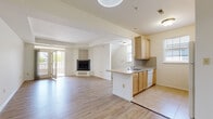 This single-floor residence is designed with an open, functional layout that connects the main living spaces seamlessly. The living area is a generous, light-filled space with light wood-style flooring and a corner fireplace, creating a warm focal point. French doors lead to a private balcony, allowing natural light to flow in and providing an outdoor retreat.

The kitchen is positioned adjacent to the living area and features a peninsula with a sink, light wood cabinetry, speckled laminate countertops, a tile backsplash, and white appliances including a dishwasher. Tile flooring in the kitchen transitions cleanly into the wood-style flooring of the main living space.

The bedrooms are carpeted and well-sized, each equipped with a ceiling fan. One bedroom benefits from a large window offering natural light and outdoor views, while another includes a walk-in closet. The bathroom is finished with tile flooring, a light wood vanity, and a tub and shower combination enclosed by sliding glass doors.

A dedicated in-unit laundry area houses a full-sized washer and dryer with overhead wire shelving for storage. Throughout, the space maintains a clean, neutral palette that contributes to a bright and airy overall ambiance.
