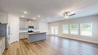 Located at 901 Porchlight Drive in Loganville, Georgia, this well-appointed two-story home offers four bedrooms and four full bathrooms across two thoughtfully designed floors. The main level is anchored by an open-concept kitchen and living room, where warm hardwood-style flooring flows throughout. The kitchen features gray shaker-style cabinetry, granite countertops, stainless steel appliances including a range, microwave, and refrigerator, and a central island with a sink. Recessed lighting and a ceiling fan complement the bright, airy living area, which is lined with large windows and glass French doors that invite abundant natural light and outdoor views. A decorative wainscoting detail adds a refined touch to the main living space. The upper floor hosts the majority of the bedrooms, including a spacious primary suite complete with a private en-suite bathroom featuring granite countertops, gray cabinetry, a large vanity mirror, and a walk-in shower. A walk-in closet with wire shelving provides generous storage. Additional bedrooms are finished with plush carpet and are serviced by well-appointed bathrooms. A dedicated laundry room with utility hookups and overhead shelving, along with multiple hallways and a staircase with classic wood and metal baluster detailing, complete this functional and stylish home.