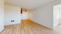Located at 1801 Shore Line Dr in Alameda, California, this two-bedroom, one-bathroom residence offers a well-organized single-floor layout designed for comfortable everyday living. Light wood-style flooring flows throughout the main living areas, complemented by crisp white walls and textured ceilings that lend a clean, bright aesthetic throughout.

The combined kitchen and living room area forms the heart of the home. The living room is generously proportioned, featuring a ceiling fan, crown molding, and open sightlines into adjacent spaces. A structural column subtly defines the transition between areas. The kitchen is efficiently designed with warm wood cabinetry, tile backsplash, stone-look countertops, and a full suite of stainless steel appliances including a refrigerator, range, and microwave.

The bathroom is a standout feature, showcasing a wide dual-sink vanity with quartz countertops, framed wood-toned mirrors, white shaker cabinetry, and a wood-plank accent wall that adds texture and warmth. Both bedrooms are carpeted for comfort, each with windows providing natural light and baseboard heating. The primary bedroom offers a comfortable footprint with a dedicated closet. The secondary bedroom also benefits from natural light and a similarly neutral, move-in-ready palette throughout.