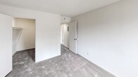 This single-floor unit offers a practical and well-organized layout designed to maximize everyday comfort. The living area is generously sized, featuring neutral-toned wall-to-wall carpeting that extends throughout the main spaces. A large window fitted with vertical blinds allows natural light to fill the room, creating a bright and open atmosphere. Adjacent to the living area, a built-in closet provides convenient storage, while a hallway connects the various rooms seamlessly.

The galley-style kitchen is efficiently laid out, featuring warm oak cabinetry with ample upper and lower storage, white laminate countertops, a double stainless steel sink, and a gas range. Light tile-style flooring and a window with horizontal blinds contribute to a clean, functional workspace.

The bedrooms are carpeted and finished with the same neutral palette, each benefiting from windows that bring in outdoor views and natural light. Closet access is provided in the primary bedroom area, and a hallway connects to the full bathroom, which includes a tub and shower combination, tile flooring, and clean white fixtures throughout.

Textured ceilings are consistent across the unit, lending a classic residential character. The thoughtful floor plan, ample storage, and functional rooms make this a practical and comfortable living space.