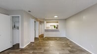 This single-story, 1-bedroom, 1-bathroom unit offers a thoughtfully designed open-concept layout with a neutral color palette and clean finishes throughout. The living room is a standout space, featuring wood-look luxury vinyl flooring, a classic fireplace, and a large sliding glass door with vertical blinds that floods the room with natural light and provides access to an outdoor area. A textured ceiling adds character to the living space.

The kitchen is accessed via a pass-through counter that also serves as a breakfast bar, making it an ideal feature for casual dining or entertaining. Inside the kitchen, white cabinetry pairs with granite-look countertops, a stainless steel sink, and black appliances including a range, microwave, dishwasher, and full-size refrigerator. Wood-look flooring continues throughout the kitchen, maintaining a cohesive design.

The bedroom is carpeted for comfort and includes a ceiling fan, a window with an outdoor view, and a dedicated closet. The bathroom features a full tub-shower combo with tiled surround, wood-look flooring, and a vanity with granite-look countertops. Additional storage is provided by a separate closet accessible from the main living area, completing this functional and well-finished single-floor residence.