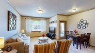 This single-story residence at 121 East Victory Road in Meridian, Idaho, offers a thoughtfully designed layout that balances comfort and functionality throughout its interconnected living spaces.

The living room serves as a welcoming central hub, featuring neutral-toned carpet, a textured ceiling, and crown molding. A large window dressed with sheer curtains admits generous natural light, while a patio door provides direct outdoor access and additional brightness to the adjoining dining area, which comfortably accommodates a full dining set.

The kitchen is a standout feature, showcasing warm honey-toned cabinetry that extends to the ceiling for ample storage, dark granite countertops, and stainless steel appliances including a range, microwave, and refrigerator. A central island with a matching granite surface and bar seating adds both workspace and casual dining versatility. Pendant lighting and recessed fixtures illuminate the space effectively, while light hardwood-style flooring ties the kitchen seamlessly to adjacent areas.

The bedrooms offer carpeted comfort, natural light through windows with outdoor views, and ample room for furnishings. The bathrooms feature wood cabinetry, dark granite vanity tops, large mirrors, and hardwood-style flooring, presenting a cohesive, refined aesthetic throughout the home.