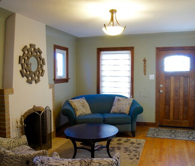 The living room has coved ceilings, original wood floors, modern paint colors and a wood burning fireplace. - 3894 Meade St