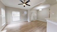 This single-story, 1-bedroom, 1-bathroom home offers a thoughtfully designed open-concept floor plan that maximizes every square foot. Light wood-look flooring flows seamlessly throughout, complemented by neutral warm-gray walls and crisp white trim, creating a clean and cohesive aesthetic.

The combined living, dining, and kitchen area forms the heart of the home. The spacious living room features a white-mantled fireplace flanked by multiple windows dressed with white blinds, allowing generous natural light to fill the space. A ceiling fan overhead adds both style and function. An elegant arched passageway connects the living area to the kitchen zone, adding architectural character.

The kitchen is well-equipped with white shaker-style cabinetry, light quartz countertops, a subway tile backsplash, and stainless steel appliances including a range, over-the-range microwave, and dishwasher. A double-basin undermount sink with a modern faucet anchors the peninsula, which opens toward the dining area.

The bedroom is a comfortable, well-proportioned retreat with light-filled windows and ample closet space. Two closets serve the unit for additional storage. The bathroom features light wood-look flooring, white shaker vanity cabinetry, and a full soaking tub with tile surround. The home also includes a dedicated laundry area and an attached garage, rounding out a practical and inviting living space.