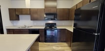 Located at 5805 S Ben Burr Rd in Spokane, Washington, this single-floor unit offers a well-designed, open-concept layout finished with consistent wood-look luxury vinyl plank flooring throughout. The living area is bright and spacious, featuring large windows with blinds and sliding glass doors that open to a private balcony, allowing generous natural light and outdoor access. A wall-unit HVAC system provides climate control directly in the living space.

The kitchen is a standout feature, outfitted with rich dark wood cabinetry extending to the upper walls for ample storage, light-toned countertops, and a full suite of black appliances including a refrigerator, range, microwave, and dishwasher. A kitchen island with additional counter space and pendant lighting enhances both functionality and style.

The bedrooms are generously sized with neutral walls, wood-look flooring, and windows that invite natural light. One bedroom includes direct access to a full bathroom, which features a dark wood vanity with a broad countertop, a tub-shower combination, and wood-look tile flooring. A second full bathroom mirrors this clean, modern aesthetic.

Additional rooms offer flexible use, with multiple outlets and neutral finishes. Dark-trimmed solid wood doors provide a cohesive, contemporary look throughout the unit, contributing to an overall ambiance that is clean, modern, and move-in ready.