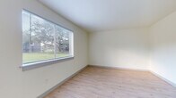 This single-floor unit offers a thoughtfully laid-out interior finished with light hardwood-style flooring that runs consistently throughout every room, creating a cohesive and easy-to-maintain living environment. The neutral, cream-toned walls provide a bright and open atmosphere across all spaces.

The kitchen is outfitted with granite-patterned countertops, a double stainless steel sink, grey cabinetry above and below the counter, and a dishwasher, offering practical functionality in a compact, efficient layout.

Multiple versatile rooms are present throughout the unit, each featuring clean white walls, light flooring, and window blinds that allow for adjustable natural light. One room benefits from a large picture window with views of surrounding greenery, while another features a window overlooking an exterior stairway. A room with a connected bathroom provides added convenience and privacy.

The bathroom is well-appointed with a granite-topped vanity, an integrated sink, a medicine cabinet mirror, and a full shower-tub combination, all finished in clean white tones that complement the rest of the unit.

Overall, this space presents a clean, minimalist aesthetic with consistent finishes throughout, offering a functional and versatile layout suitable for a variety of uses.