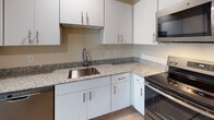 Located at 1012 Shiloh Way in Morrisville, NC, this single-floor unit offers a bright, contemporary living environment defined by a cohesive neutral color palette and light wood-style flooring throughout. The open-concept living and kitchen area is thoughtfully designed, allowing for a seamless flow between spaces. The kitchen is well-equipped with crisp white shaker-style cabinetry, granite countertops, a stainless steel sink, and a full suite of stainless steel appliances including a dishwasher, range, and microwave. Recessed lighting illuminates the space effectively. Multiple bedrooms provide comfortable accommodations, each featuring light wood-style flooring, neutral walls, and windows with blinds and curtains that invite natural light and offer views of the surrounding greenery. The unit includes two bathrooms: one featuring a granite-topped vanity with white cabinetry, a large mirror, and a glass-door shower, while the second bathroom offers a matching vanity and a full tub-shower combination. Clean lines, consistent finishes, and a neutral, move-in-ready aesthetic define the overall ambiance of this well-maintained Morrisville residence.