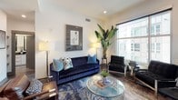 Located in the heart of Charlotte, NC, this contemporary single-floor residence at 558 E Stonewall St offers a sophisticated urban living experience with thoughtfully designed spaces throughout. The open-concept kitchen is a standout feature, boasting sleek white cabinetry, stainless steel appliances including a built-in microwave and double wall oven, a tile backsplash, and a generous quartz-topped island with seating — all illuminated by stylish pendant lighting and set atop rich hardwood flooring. The living area is bright and welcoming, with large windows offering views of the surrounding cityscape, providing a comfortable setting with ample natural light. The bedroom is a serene retreat, featuring large windows that frame urban views, tray ceiling detailing, and plush carpeting. The en-suite bathroom is elegantly appointed with large-format tile flooring, a glass-enclosed shower, a soaking tub, and a floating double vanity with dark stone countertops. A well-organized walk-in closet with custom shelving and hanging rods provides generous storage. Throughout, the residence maintains a cohesive modern aesthetic with clean lines, neutral tones, and refined finishes that complement its prime downtown Charlotte location.