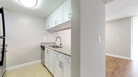 This single-floor residence offers a clean, functional layout designed for comfortable everyday living. The living area features warm hardwood-style flooring and is illuminated by track lighting, seamlessly connecting to the kitchen via a convenient pass-through counter finished with granite-style countertops. The kitchen is well-equipped with stainless steel appliances, including a range, over-the-range microwave, and dishwasher, complemented by white cabinetry and light tile flooring throughout.

A central hallway connects the main living spaces to the private areas of the home, with hardwood-style flooring transitioning to plush carpet in each of the bedrooms. The bedrooms are generously sized, each featuring natural light through blinds-equipped windows and ample storage provided by double bifold closets. The primary bedroom is notably spacious, offering a comfortable retreat.

The bathrooms are finished with granite-topped vanities, undermount sinks, and chrome fixtures. Each bathroom includes a full tub-and-shower combination with clean white tile surrounds and tile flooring. Textured ceilings are consistent throughout the space, and neutral gray walls create a cohesive, move-in-ready aesthetic across all rooms.