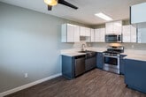 Located at 120 S Grand Ave in Anaheim, California, this single-floor unit offers a well-designed layout that balances functionality with a clean, contemporary aesthetic. Light gray walls and wood-look flooring run throughout the space, creating a cohesive and modern feel.

The kitchen is a standout feature, showcasing a two-tone design with glossy white upper cabinetry and slate blue lower cabinets, paired with crisp white quartz countertops. Stainless steel appliances include a gas range, over-the-range microwave, and dishwasher, all complemented by a skylight that brightens the workspace. The kitchen opens toward the living area, which is spacious and filled with natural light from a large window. A wall-mounted HVAC unit ensures year-round comfort.

The living and dining areas provide generous open space with smooth transitions to the kitchen and additional rooms. Ceiling fans with integrated lighting are present in multiple rooms, including a bedroom that benefits from a bright window and the same warm wood-look flooring.

The bathroom is finished with speckled quartz countertops, an undermount sink, chrome fixtures, and a wide mirrored medicine cabinet with overhead lighting, offering a bright and functional space. Overall, this unit presents a refreshed, move-in-ready interior with modern finishes throughout.