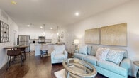 Located at 13708 Wimbledon Loop in Little Rock, Arkansas, this single-story home offers a thoughtfully designed open-concept layout that seamlessly connects the main living areas. The living room features rich dark hardwood flooring, recessed lighting, and French doors that invite natural light while providing outdoor access. The space is comfortably sized, accommodating a relaxed seating arrangement centered around a glass-topped coffee table.

The kitchen is a standout feature, showcasing crisp white shaker-style cabinetry, light granite countertops, and stainless steel appliances including a range, microwave, and refrigerator. A peninsula with bar seating and pendant lighting overhead creates a natural gathering spot and adds to the kitchen's functional appeal. The dark hardwood flooring continues throughout this area, maintaining a cohesive aesthetic.

The bedroom is a calm retreat, finished with plush carpeting, a ceiling fan, and a generously sized window that allows ample natural light. The neutral tones throughout the room contribute to a restful atmosphere.

The bathroom is cleanly finished with a tub-shower combination and wood-look flooring, maintaining the home's consistent, modern style. Overall, the space presents a bright, neutral palette and a practical, comfortable design throughout.