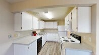 Located at 2405 N Cherry St in Spokane Valley, WA, this single-floor unit offers a clean, functional layout designed for comfortable everyday living. The open living and dining area is finished with durable luxury vinyl plank flooring in a soft grey wood tone, neutral warm beige walls, and large vertical-blind-covered sliding glass doors that invite an abundance of natural light while providing outdoor views. A wall-mounted air conditioning unit ensures year-round comfort in this space.

The kitchen is well-appointed with ample white cabinetry, light speckled countertops, a double stainless steel sink, and a full suite of white appliances including a refrigerator, electric range, and over-the-range microwave. A black dishwasher adds modern convenience. Bright overhead fluorescent lighting keeps the kitchen well-illuminated throughout the day.

The bedrooms are carpeted in neutral tones, offering a soft, quiet retreat. Each room features natural light from windows with blinds, wall heating vents, and generous closet space with sliding doors and built-in shelving. A textured ceiling in the living area adds subtle architectural character. Overall, the space presents a tidy, move-in-ready environment with practical finishes throughout.