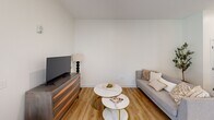 Located at 27 Park Rd in West Hartford, CT, this thoughtfully designed two-bedroom, one-bathroom residence offers a clean, modern aesthetic across a well-appointed single floor. Warm hardwood-style flooring flows throughout, tying the spaces together in a cohesive, contemporary palette of whites and neutrals.

The open-concept kitchen and living area serves as the heart of the home. The kitchen features sleek flat-front cabinetry in a soft gray finish, stainless steel appliances including a French door refrigerator and range, a crisp white quartz countertop, a blue subway tile backsplash, and a central island with pendant lighting — ideal for both everyday meals and entertaining.

The living room is bright and inviting, benefiting from large windows that frame outdoor views of greenery and the surrounding neighborhood, allowing ample natural light to fill the space.

The spacious primary bedroom offers generous room to move, with large windows, soft neutral walls, and a relaxed, airy ambiance. The second bedroom is equally well-lit and versatile.

The bathroom is finished to a high standard, showcasing a warm wood vanity with white quartz countertop, an undermount sink with matte black fixtures, a backlit LED mirror, and a tiled shower-tub combination — a refined, spa-like retreat within a compact footprint.