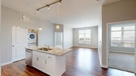 Located at 822 Williams Ave in Grandview Heights, OH, this 2-bedroom, 2-bathroom residence offers a thoughtfully designed single-floor layout. The open-concept kitchen and living area serves as the heart of the home, showcasing rich hardwood-style flooring, a granite-topped island with a double sink, pendant lighting, and a full suite of stainless steel appliances. White cabinetry and track lighting complete the kitchen's clean, modern aesthetic. A stacked washer and dryer unit is conveniently tucked nearby. The living room receives generous natural light through large windows and includes access to an outdoor area via a glass door. Both bedrooms are carpeted and well-lit, with the primary bedroom featuring an en-suite bathroom equipped with a wide vanity, white cabinetry, and a framed mirror. The second bathroom mirrors this refined style with similar finishes and hardwood-style flooring. Two closets provide ample storage, including a walk-in with wire shelving. Neutral gray tones throughout create a cohesive, contemporary ambiance, making this a comfortable and functional residence in a desirable Ohio community.
