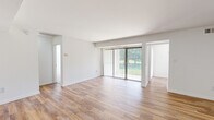 This 1-bedroom, 1-bathroom residence in Columbia, MD is thoughtfully laid out across a single floor, offering a clean and modern living environment. The living room is a standout space, featuring light wood-style flooring, crisp white walls, and a large sliding glass door fitted with vertical blinds that floods the room with natural light and provides views of the surrounding greenery outdoors. The open sightlines from the living area extend toward the hallway leading to the bathroom, enhancing the sense of space throughout.

The kitchen is efficiently designed with light wood cabinetry, marble-style countertops, stainless steel appliances including a full-size refrigerator and dishwasher, and a window that brings in additional natural light. The wood-style flooring continues seamlessly from the living area into the kitchen.

The bedroom is a generously sized, carpeted retreat featuring windows with views of lush outdoor greenery, providing a quiet and comfortable atmosphere. A closet offers convenient storage within the room.

A connecting hallway links the main living areas to the bathroom and bedroom, giving the unit a practical and well-organized flow. Throughout the space, the neutral color palette, consistent finishes, and abundance of natural light create a bright, welcoming ambiance suited to everyday living.