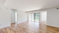 This 1-bedroom, 1-bathroom residence in Columbia, MD is thoughtfully laid out across a single floor, offering a clean and modern living environment. The living room is a standout space, featuring light wood-style flooring, crisp white walls, and a large sliding glass door fitted with vertical blinds that floods the room with natural light and provides views of the surrounding greenery outdoors. The open sightlines from the living area extend toward the hallway leading to the bathroom, enhancing the sense of space throughout.

The kitchen is efficiently designed with light wood cabinetry, marble-style countertops, stainless steel appliances including a full-size refrigerator and dishwasher, and a window that brings in additional natural light. The wood-style flooring continues seamlessly from the living area into the kitchen.

The bedroom is a generously sized, carpeted retreat featuring windows with views of lush outdoor greenery, providing a quiet and comfortable atmosphere. A closet offers convenient storage within the room.

A connecting hallway links the main living areas to the bathroom and bedroom, giving the unit a practical and well-organized flow. Throughout the space, the neutral color palette, consistent finishes, and abundance of natural light create a bright, welcoming ambiance suited to everyday living.