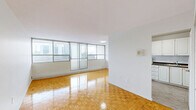 Located at 1900 Bloor St E in Mississauga, this well-laid-out two-bedroom, two-bathroom unit offers a comfortable and functional living space across a single floor. The interior is defined by warm, glossy parquet flooring that runs throughout the main living areas and bedrooms, adding a classic character to the space.

The living room is generously proportioned, featuring a wide wall of floor-to-ceiling sliding glass windows and doors that flood the room with natural light and provide direct access to the balcony. The city skyline views visible from multiple rooms lend the unit an elevated, airy feel.

Both bedrooms are well-sized, each featuring large windows with baseboard heating beneath them, ensuring comfort year-round while also framing the surrounding urban views. The primary bedroom offers a notably comfortable footprint with ample wall space.

The two bathrooms are cleanly finished with white cabinetry, granite-style countertops, integrated sinks, and large mirrors with overhead lighting. The main bathroom includes a tiled shower area. The kitchen connects conveniently to the living space, with tile flooring distinguishing it from the rest of the unit. Throughout, the unit maintains a bright, neutral palette with white walls and clean finishes, creating a move-in-ready environment.