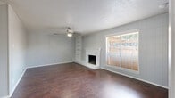 Located at 8623 Starcrest Dr in San Antonio, TX, this single-floor, 2-bedroom, 2-bathroom residence offers a well-organized layout with a comfortable and functional design throughout. The living room serves as the heart of the home, highlighted by rich hardwood-style flooring, a classic white brick fireplace, built-in shelving, a ceiling fan, and a large window that fills the space with natural light. An adjacent dining or flex area shares the same flooring and beamed ceiling detail, adding architectural character. The galley-style kitchen is thoughtfully appointed with white cabinetry, granite countertops, a mosaic tile backsplash, stainless steel appliances including a dishwasher and refrigerator, and a gas range. Both bedrooms feature plush carpet, ceiling fans with light fixtures, and windows with blinds that provide natural light and privacy. The primary bedroom offers a generous footprint with ample room for furnishings. The two bathrooms are finished with granite-topped vanities, white cabinetry, and hardwood-style flooring. One bathroom includes an accessible tub/shower combo with grab bars, while the second features a walk-in shower. Two hallways connect the living areas to the private spaces, contributing to a smooth and practical flow throughout the home.