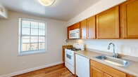 Located at 3100 Southgate Drive in Alexandria, Virginia, this one-bedroom, one-bathroom residence offers a well-organized single-floor layout designed for comfortable everyday living. The expansive living room is a standout feature, showcasing plush wall-to-wall carpeting, neutral walls, and large sliding glass doors that open to a private balcony with outdoor views — filling the room with generous natural light. Track lighting adds a functional accent near the kitchen entry. The kitchen is thoughtfully appointed with warm honey-toned wood cabinetry, light laminate countertops, hardwood-style flooring, and white appliances including a gas range, over-the-range microwave, dishwasher, and refrigerator. A window above the counter brings in additional natural light. The bedroom is a comfortable, carpeted retreat with its own window and direct access to the hallway. Two closets provide ample storage throughout the unit. The bathroom features a clean, white-tiled tub-shower combination with chrome fixtures. A connecting hallway ties the rooms together seamlessly, creating a practical and cohesive flow throughout this well-maintained Alexandria residence.