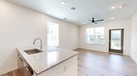 Located in Saint Augustine, FL, this thoughtfully designed one-bedroom, one-bathroom residence offers a clean, modern aesthetic across a single floor. Wood-look plank flooring runs throughout the entire space, providing a warm and cohesive foundation for each room.

The open-concept kitchen and living area serves as the heart of the home. The kitchen is outfitted with flat-front, light wood cabinetry extending to the ceiling for ample storage, a full suite of stainless steel appliances including a french-door refrigerator, electric range, and over-the-range microwave, and a large center island featuring a granite countertop and undermount sink — ideal for both meal preparation and casual dining.

The living area receives natural light through a glass door fitted with blinds, offering access to the outdoors. The spacious bedroom features a ceiling fan with integrated lighting, a generous window that fills the room with natural light, and double panel doors leading to a sizable closet. The clean white walls and neutral palette create a bright, airy atmosphere.

The bathroom is well-appointed with a wood-toned vanity, granite countertop, undermount sink, wall-mounted storage cabinet, and wood-look flooring that continues from the rest of the home, maintaining a consistent, modern design language throughout.