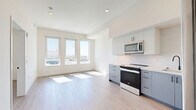 This contemporary 580 square foot apartment in Los Angeles offers a harmonious blend of style and functionality. The open floor plan maximizes the use of space, creating a seamless flow between living areas. The kitchen is a highlight, boasting sleek stainless steel appliances, including a large refrigerator, built-in microwave, and modern range. Two-tone cabinetry in white and blue-gray adds visual interest, while the light-colored backsplash enhances the bright, airy feel.

The spacious bedroom, measuring 160 square feet, features a large window that floods the space with natural light and offers city views. Light wood-look flooring runs throughout the apartment, unifying the design and adding warmth. The bathroom is generously sized, with a contemporary vanity and a combination tub-shower with dark tiled walls, creating a striking contrast to the overall light palette.

High ceilings and crisp white walls contribute to the apartment's sense of spaciousness. The unit's layout is efficient, with well-defined areas for living, dining, and sleeping. This apartment represents modern urban living at its finest, offering a comfortable and stylish home in the heart of Los Angeles.