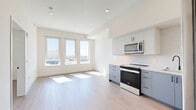 Located at 1233 N Highland Ave in the heart of Hollywood, Los Angeles, this well-appointed 1-bedroom, 1-bathroom unit offers a thoughtfully designed layout across a single floor. Light hardwood flooring runs throughout, complementing the clean, modern aesthetic found in every room.

The open-concept kitchen and living area serves as the centerpiece of the unit. The kitchen is outfitted with two-tone cabinetry — soft grey lower cabinets paired with white uppers — alongside a marble-style backsplash, quartz countertops, and a full suite of stainless steel appliances including a range, over-the-range microwave, dishwasher, and refrigerator. A bank of large windows floods the living area with natural light and frames sweeping city views.

The bedroom is a bright, comfortable retreat with its own window offering additional city views, a dedicated closet, and a clean, neutral palette. The bathroom features a combination tub and shower clad in rich dark tile, accented by matte black fixtures, a blue vanity with a white countertop, and wood-look flooring that ties the space together.

Additional conveniences include an in-unit laundry area and a hallway that provides smooth circulation between all rooms. The unit's modern finishes, natural light, and urban views make it a standout offering in the Hollywood neighborhood.