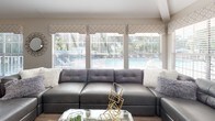 This well-appointed single-floor space showcases a cohesive contemporary design throughout, highlighted by warm wood-look flooring, neutral toned walls, and vaulted ceilings that lend an airy, open feel to the layout.

The kitchen is a standout feature, offering dark espresso cabinetry paired with granite countertops, stainless steel appliances, and a spacious island with seating for multiple bar-height chairs. Pendant lighting hangs above the island, and track lighting accents the soaring ceiling, creating a bright and functional workspace that flows seamlessly into the surrounding living areas.

The main living area is generously sized, anchored by a large sectional sofa and framed by a bank of windows that invite natural light and outdoor views, including a glimpse of a pool area beyond. A second, more intimate sitting room provides additional lounge space, featuring a wall-mounted television, a sleek media console, and a mix of modern seating.

The dining area benefits from its own vaulted ceiling and an interior glass door that connects to an adjacent room, enhancing the sense of depth and flow. A round glass dining table with upholstered chairs occupies the center of the space.

Overall, the layout is thoughtfully arranged, with distinct yet interconnected zones that balance openness with purposeful design.