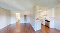 This well-appointed 1-bedroom, 1-bathroom unit is thoughtfully laid out across a single floor, offering an efficient and functional living space. The open-concept living room and kitchen area serves as the heart of the unit, featuring warm hardwood-style flooring, neutral-toned walls, and a textured ceiling that adds character throughout. Large windows in the living area fill the space with natural light and provide pleasant outdoor views of surrounding greenery and a pool area, enhancing the overall sense of openness.

The kitchen is designed for practicality, boasting white shaker-style cabinetry, light countertops, a stainless steel sink, a gas range, a dishwasher, and a built-in microwave. A peninsula counter neatly separates the kitchen from the living area, creating a defined yet connected layout.

The bedroom is a comfortable, carpeted retreat featuring a large closet, a window with outdoor views, and a wall vent for climate control. The adjoining bathroom includes a wide vanity with a light countertop, a large mirror, and overhead lighting.

Throughout the unit, consistent design choices — including white trim, neutral walls, and cohesive flooring — create a clean, move-in-ready aesthetic suited for practical, everyday living.