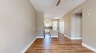 This cozy 620 square foot apartment offers a thoughtful layout that maximizes space efficiency. The single-floor design includes one bedroom, measuring 140 square feet, and one bathroom. The heart of the home is an open-concept kitchen and living room area, promoting a sense of spaciousness and flow.

The interior is characterized by a neutral color palette, with warm beige walls that create a welcoming atmosphere. The flooring throughout is a durable and attractive wood-look material, likely luxury vinyl plank, in a rich medium brown tone that adds warmth and character to the space.

Large windows and a glass-paned door, both featuring crisp white trim, allow ample natural light to flood the interior, making the space feel bright and airy. The windows are equipped with both blinds and what appears to be transom windows above, offering flexibility in light control and privacy.

The apartment includes modern amenities, as evidenced by the presence of multiple electrical outlets and switches visible in the image. A hallway and closet provide additional functionality and storage options.

While compact, this apartment's thoughtful design and finishes create a comfortable and contemporary living space, ideal for individuals or couples seeking an efficient urban dwelling.