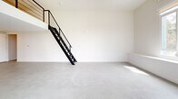 Located at 2735 E 6th St in the heart of East Los Angeles, this modern two-story home offers a thoughtfully designed open-concept layout. The main floor features polished concrete flooring throughout, lending a clean, contemporary aesthetic to the generously sized living, dining, and kitchen area. Bright white walls and multiple windows invite abundant natural light, enhancing the sense of openness. A striking black metal staircase with cable railing serves as a functional architectural focal point, leading to the upper level. The kitchen is well-appointed with warm wood-toned cabinetry, white countertops, a tile backsplash, and stainless steel appliances including a refrigerator, microwave, and range. An in-unit washer is also conveniently integrated into the kitchen area. High ceilings on the main floor add to the airy, loft-like atmosphere. Upstairs, the private bedroom offers a more intimate setting with carpet flooring and an adjoining bathroom complete with a glass-enclosed shower. The overall design balances minimalist modern finishes with practical functionality, making this a well-suited home for those seeking contemporary urban living in Los Angeles.