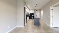 Located at 9410 E Ray Rd in Mesa, Arizona, this 1-bedroom, 1-bathroom unit offers a clean, modern aesthetic throughout its efficiently designed single-floor layout. The open-concept living and kitchen area serves as the heart of the space, featuring light-toned tile flooring that flows seamlessly throughout. The kitchen is outfitted with crisp white shaker cabinetry reaching toward the ceiling, dark granite-style countertops, black appliances including a refrigerator, range, and over-the-range microwave, and a central island with pendant lighting overhead — ideal for both meal prep and casual dining. Recessed lighting and neutral warm-beige walls create a bright, welcoming atmosphere.

The bedroom is a comfortable, well-proportioned retreat with wood-look plank flooring, soft neutral walls, and a window with outdoor views and access to a balcony, allowing for natural light and fresh air. A dedicated closet provides ample storage. The full bathroom is finished with light tile flooring, a tub-shower combination with white subway tile surround and a curved chrome rod, a toilet, and a vanity with granite-style countertops and gray cabinetry. A hallway connects the living areas to the private spaces, completing this tidy and functional floor plan.
