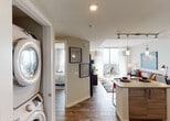 Located in the heart of Fort Lauderdale, this well-appointed single-floor residence offers a thoughtfully designed open-concept layout that seamlessly connects the kitchen, living, and dining areas. The kitchen is outfitted with sleek two-tone cabinetry — combining high-gloss white uppers with warm wood-grain lower cabinets — complemented by stainless steel appliances including a side-by-side refrigerator, electric range, and built-in microwave, all set atop durable wood-look flooring. The living area is a bright, airy space anchored by expansive floor-to-ceiling windows and sliding glass doors that open to a private balcony, offering sweeping panoramic views of the Fort Lauderdale skyline. Natural light floods the interior, enhancing the modern, neutral color palette throughout. The bedroom features large windows with the same commanding views, a walk-in closet, and ample space for a generous furniture arrangement. The bathroom includes a full soaking tub with shower, large-format tile surround, and wood-toned vanity cabinetry. A stacked in-unit washer and dryer adds everyday convenience. Track lighting, recessed fixtures, and carefully selected finishes contribute to the residence's clean, contemporary aesthetic.