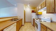 Located at 1010 River Trail Circle in Kiel, Wisconsin, this one-bedroom, one-bathroom unit offers a practical and well-organized single-floor layout. The combined living, dining, and kitchen area forms the heart of the home, with the living and dining space featuring plush carpeting, baseboard heating, and a sliding glass door that opens to a private balcony overlooking the surrounding neighborhood. Natural light fills the area, creating a bright and welcoming atmosphere. A wall-mounted air conditioning unit provides additional climate control comfort.

The kitchen is efficiently designed with warm oak cabinetry lining both sides of the galley-style layout, offering ample upper and lower storage. It is equipped with a full suite of white appliances, including a range, refrigerator, and dishwasher, set atop durable tile-style flooring.

The bedroom is a generously sized, carpeted retreat with a large window that invites natural light and views of the neighborhood. Two closets throughout the unit provide excellent storage capacity. The full bathroom features a single-sink vanity with oak cabinetry, a tub-shower combination, and tile flooring. A dedicated laundry area and staircase access round out the functional layout of this well-appointed Kiel residence.