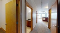 This single-floor unit blends functional design with comfortable living across a well-organized layout. A carpeted hallway serves as the central spine of the unit, connecting the main living areas to the private spaces. Warm wood trim and natural-toned finishes carry throughout, lending visual consistency from room to room.

The kitchen is well-appointed with rich wood cabinetry extending to the ceiling, granite countertops, and stainless steel appliances including a refrigerator, electric range, and built-in microwave. Tile flooring and a sink positioned along the perimeter make the space both practical and polished.

The main living area is a standout, featuring a trio of arched windows with bold blue frames that flood the room with natural light and offer views of the surrounding urban landscape. The carpeted floor and open feel make this a welcoming focal point of the unit.

The bedrooms are carpeted and bright, with interior transom-style windows that allow light to filter between spaces. The bathroom includes a full tub-shower combination, tile flooring, and a separate vanity area with wood cabinetry and granite counters, completing the unit's cohesive, practical aesthetic.