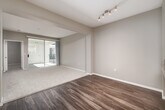 Located at 8465 Regents Rd in San Diego's University City neighborhood, this 2-bedroom, 2-bathroom residence offers a well-designed single-floor layout. The open-concept kitchen and living area serves as the heart of the home, where the kitchen is outfitted with stainless steel appliances—including a refrigerator, range, microwave, and dishwasher—complemented by white cabinetry, granite-style countertops, and wood-look flooring. A peninsula with additional counter space flows seamlessly into the living area, which features track lighting and sliding glass doors that open to a private balcony, allowing natural light to fill the space. The living room transitions between wood-look and plush carpeted flooring, creating distinct functional zones. The generously sized primary bedroom includes a ceiling fan, soft carpeting, and direct access to a private en-suite bathroom featuring a granite vanity, white cabinetry, and a tub-shower combination. A spacious walk-in closet with wire shelving provides ample storage. The second bedroom also features carpet and a ceiling fan. Both bathrooms mirror the same clean, neutral finishes found throughout. A connecting hallway and two dedicated closets add to the home's practical storage solutions.