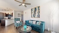 This single-story, 2-bedroom, 2-bathroom residence offers a thoughtfully designed layout that maximizes comfort and functionality. The entry foyer welcomes you with a paneled front door flanked by two windows fitted with horizontal blinds, allowing natural light to filter in while maintaining privacy.

The open-concept living and kitchen area forms the heart of the home. The living room features wood-style flooring, a ceiling fan with light fixture, and neutral white walls that create a bright and airy atmosphere. The kitchen is equipped with dark cabinetry, stainless steel appliances including a refrigerator and microwave, a granite-style countertop, and track lighting overhead — all visible from the living space.

A hallway connects the living area to the private quarters. Both bedrooms are carpeted and well-lit, with windows dressed in blinds and curtains. The spacious primary bedroom includes a ceiling fan, large windows, and ample room for a full furniture suite. The second bedroom is similarly comfortable. Each bedroom is served by its own bathroom; the bathrooms feature dark wood vanity cabinetry, white countertops, wood-look tile flooring, and a tub-shower combination. A dedicated closet provides additional storage within the unit.