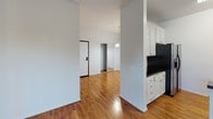 This single-story space in the North Hollywood neighborhood of Los Angeles, CA (91602) offers a clean, functional layout with a cohesive design throughout. Warm hardwood flooring runs continuously across the living areas, bedroom, and kitchen, creating a unified and inviting atmosphere.

The kitchen is well-appointed with white shaker-style cabinetry, dark granite countertops, a classic white subway tile backsplash, and stainless steel appliances including a gas range, over-the-range microwave, and a double-basin sink. A peninsula-style counter separates the kitchen from the adjacent living area, offering an open, connected feel.

The living area benefits from notably high ceilings, enhancing the sense of space and airflow throughout. Natural light enters through windows fitted with blinds, brightening the neutral white walls. The bedroom is a calm, simple space with hardwood flooring and a window with shuttered blinds providing privacy and light control.

The bathroom features a white vanity with a beige stone-toned countertop, a framed mirror, a three-bulb vanity light fixture, chrome hardware, and a full-size tub and shower combination. A small window above the shower allows natural light in. The overall ambiance of the space is clean, modern, and move-in ready.