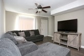 This two-floor residence offers a practical and comfortable layout designed for everyday living. The kitchen is well-equipped with wood-trimmed cabinetry, a mosaic tile backsplash, stainless steel appliances including an electric range and dishwasher, and durable hardwood-style flooring. Natural light filters in through a window with blinds, adding brightness to the space. The living area features hardwood-style flooring, a textured ceiling, a ceiling fan, and a classic fireplace that serves as a natural focal point. A large sectional sofa and vertical window blinds contribute to a relaxed, welcoming atmosphere. The bedrooms are carpeted and finished with neutral-toned walls and textured ceilings. Each room is generously sized, offering comfortable accommodations with ceiling light fixtures and window treatments for privacy. The bathroom includes a shower-tub combination with a curtain, a vanity, and hardwood-style flooring in a clean, understated design. A dedicated laundry area houses a full-sized top-loading washer and dryer with overhead shelving for storage. Throughout the home, a consistent neutral color palette and practical finishes create a cohesive and livable environment across both floors.