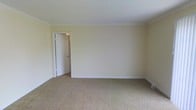 This single-floor residence offers a straightforward and well-maintained interior designed for comfortable living. The space is defined by its clean, neutral aesthetic, with soft cream-toned walls that create a bright and welcoming atmosphere throughout. The flooring features plush wall-to-wall carpeting in a warm beige tone, adding comfort underfoot and contributing to a cozy, quiet environment. White baseboards provide a crisp contrast against the carpeted floors, lending the space a tidy, finished appearance. The ceiling is smooth and painted white, enhancing the sense of openness and light within the room. A white interior door provides access between rooms, and the overall layout appears functional and uncluttered. The simplicity of the design allows for versatile furnishing options, making it easy to personalize the space to suit a variety of needs and styles. The neutral color palette throughout ensures a cohesive and harmonious look from room to room. Overall, this single-floor space presents a clean, move-in-ready interior with a calm and understated character well-suited for everyday residential use.