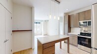 Located at 1880 English St in Maplewood, MN, this 2-bedroom, 1-bathroom unit offers a well-designed, single-floor layout that makes efficient use of its space. The open-concept kitchen and living area serves as the heart of the home, featuring light wood-tone cabinetry, stainless steel appliances including a range, microwave, refrigerator, and dishwasher, and a generous central island with pendant lighting overhead — ideal for both meal prep and casual dining. Light hardwood-style flooring runs throughout the main living areas, enhancing the bright, airy atmosphere created by large windows that invite natural light. The living room is spacious with exposed ductwork adding a modern, industrial touch to the clean white walls. Both bedrooms are carpeted and well-proportioned, with the primary bedroom featuring a large window with outdoor views. Multiple closets throughout provide ample storage. The full bathroom includes a soaking tub with shower, tile flooring, and a wood-toned vanity with a clean white countertop. A dedicated laundry area adds everyday convenience. The overall ambiance is modern and fresh, with a neutral palette that offers a versatile canvas for personalization.