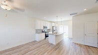 Located on Mulberry Blvd in Port Wentworth, Georgia, this two-story home offers a thoughtfully designed layout spread across two well-proportioned floors. The main level welcomes you through a bright, paneled front door into an open entryway with light wood-look flooring that flows seamlessly into the combined kitchen and living area. The kitchen is a standout feature, showcasing crisp white shaker cabinetry, a gray subway tile backsplash, stainless steel appliances, and a large central island topped with granite countertops and pendant lighting overhead. A sliding glass door connects the kitchen to the outdoors, filling the space with natural light.

Upstairs, the spacious primary bedroom features plush carpeting, a ceiling fan, and direct access to a dedicated closet and a full bathroom with a dual-sink granite vanity and dual mirrors. The second bedroom is equally comfortable, with carpeting, a ceiling fan, and a bright window with neighborhood views. A conveniently located laundry room with a washer and dryer completes the upper level. A second full bathroom on this floor features a window for natural ventilation and light. The home's clean, neutral palette and modern finishes create a bright, welcoming atmosphere throughout.