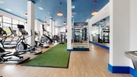 Located at 1212 Main St in Hartford, CT, this single-floor fitness center offers a comprehensive and well-designed workout environment. The space is defined by its striking blue ceiling accents, crisp white walls with bold blue baseboards, and warm wood-tone flooring throughout, creating a vibrant and energizing atmosphere.

The main cardio area features a row of treadmills and elliptical machines positioned directly in front of expansive floor-to-ceiling windows, flooding the space with natural light and offering open views of the surrounding streetscape. Red pendant lights hang from the soaring ceilings, adding an industrial-modern touch alongside ceiling fans that keep the air circulating throughout.

A dedicated functional training zone includes a turf runway, a Pennant-branded functional training rig, cable machines, and weight benches, providing ample space for dynamic and strength-based workouts. Full-length mirrors line the walls, enhancing the sense of openness.

A separate studio room is equipped with indoor cycling bikes, a large digital display wall for guided workouts, and mirrored walls — ideal for group fitness classes. An adjoining multi-use room houses a rack of medicine balls, dumbbells, resistance equipment, and a stationary bike, catering to functional and cross-training exercises.

Overall, this facility combines modern design with a diverse range of high-quality equipment to support a full spectrum of fitness needs.