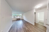 Located at 4981 Bathurst Street in North York, Toronto, this 1-bedroom, 1-bathroom unit offers a thoughtfully designed layout with modern finishes throughout. The space flows through a hallway entrance into a bright, open living area characterized by warm hardwood-style flooring and clean white walls that maximize the sense of space.

The kitchen is a standout feature, boasting white shaker-style cabinetry, a classic white subway tile backsplash, grey countertops, a stainless steel sink, and a full suite of stainless steel appliances including a refrigerator, electric range, and over-the-range microwave. Light tile flooring and a window overlooking the outdoors make this a bright and functional cooking space.

The bedroom offers a comfortable and private retreat, featuring the same warm hardwood-style flooring, a window that brings in natural light and outdoor views, a baseboard radiator for heating, and a built-in closet with sleek mirrored sliding doors that add depth and elegance to the room.

The bathroom is finished with crisp white subway tiles from floor to ceiling around the tub-shower combination, complemented by chrome fixtures and a clean, minimalist aesthetic. The overall ambiance of the unit is modern, bright, and move-in ready, making it a practical and attractive urban residence.