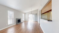 This well-appointed 2-bedroom, 2-bathroom single-floor residence offers a thoughtfully designed layout that maximizes its comfortable footprint. The open-concept living and dining area serves as the heart of the home, highlighted by vaulted ceilings that lend a sense of spaciousness and a classic brick fireplace that anchors the room. Warm hardwood-style flooring runs throughout, complementing the bright, neutral color palette. A pendant light fixture adds a stylish focal point, while a sliding glass door floods the space with natural light and provides outdoor access.

The kitchen is designed for functionality, featuring a galley-style layout with ample oak cabinetry, dark granite-style countertops, white appliances including a range, refrigerator, and dishwasher, and a pass-through counter that connects to the living area. A window above the sink brings in additional natural light.

The primary bedroom offers generous proportions, dual closets with bifold doors, hardwood-style flooring, and a ceiling fan with integrated lighting. The bathrooms are equipped with oak vanity cabinetry, dark countertops, and lighted mirrors. Two hallways and two closets provide additional storage and connectivity throughout the unit.