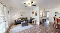 Located at 1111 W Saint Mary's Rd in Tucson, AZ, this well-appointed single-story, one-bedroom, one-bathroom unit offers a thoughtfully arranged layout across a compact yet functional floor plan. The open living room is anchored by rich wood-look flooring, a ceiling fan with light fixture, and large shuttered French doors that invite abundant natural light. A decorative arched pass-through connects the living area to the kitchen, adding a charming architectural touch. The kitchen features warm, solid wood cabinetry, marble-look countertops, wood-look flooring, and white appliances including a refrigerator, electric range with overhead microwave, and dishwasher. A separate dining area provides a defined space for meals, complete with its own ceiling light. The generously sized bedroom is finished with plush carpet, a ceiling fan, a natural light window, and a sliding-door closet offering ample storage. The full bathroom includes a tub-shower combo, wood cabinetry with a marble-look vanity top, and wood-look flooring. A connecting hallway ties all rooms together efficiently. Arched details throughout the unit lend a distinct Southwestern character to this Tucson home.